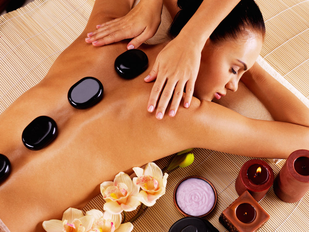 Adult woman having hot stone massage in spa salon.